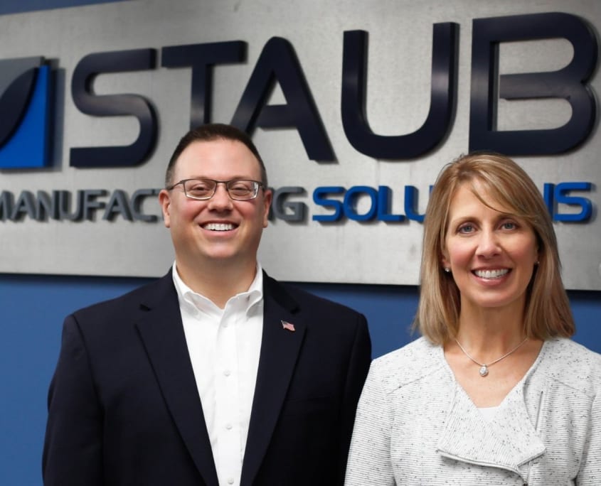 Steve Staub and Sandy Keplinger stand in front of Staub Manufacturing sign.